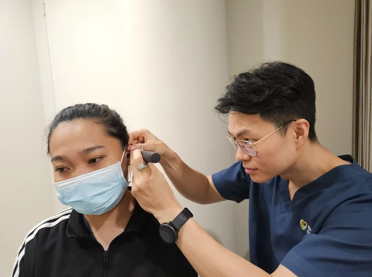 Doctor performing an otoscope examination of a patient's ear canal before ear wax removal